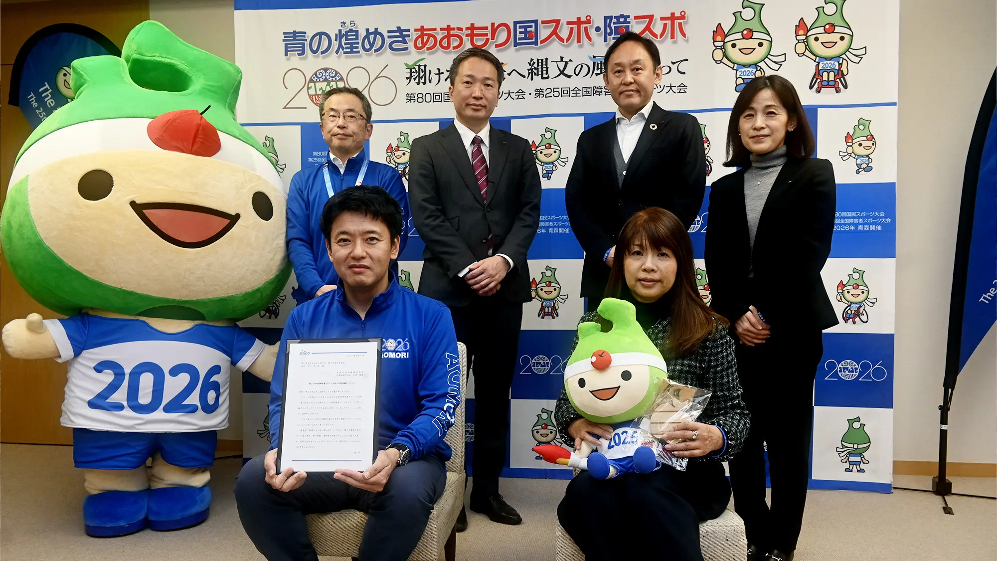 青森県知事と大枝恭子さま。その後ろに左からアップリート君と国スポ・障スポ事務局長、大同生命保険株式会社の皆様が並んでいる